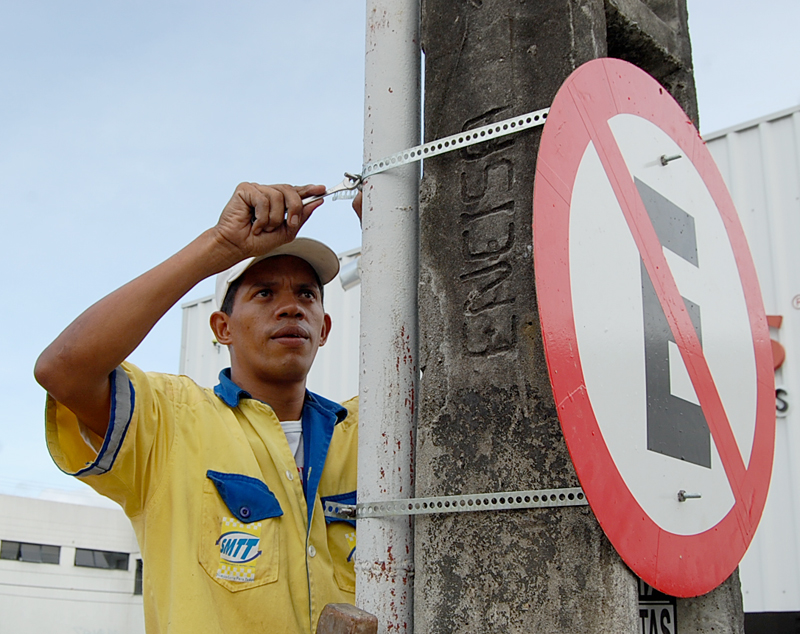 Funcionário da Smtt fixando placa proibido estacionar.
